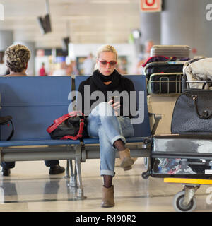 Weibliche Reisende mit Handy während der Wartezeit am Flughafen. Stockfoto