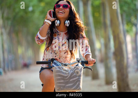 Hübsche junge Mädchen reiten Fahrrad und am Telefon zu sprechen. Stockfoto