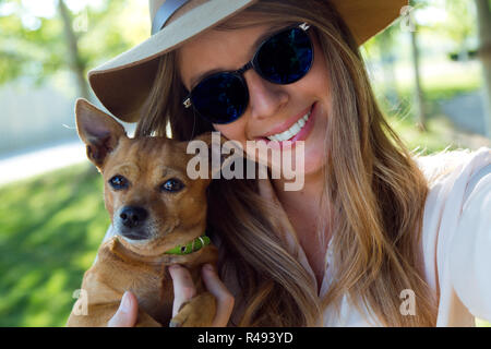 Schöne junge Frau an der Kamera, die mit Ihrem Hund. Stockfoto