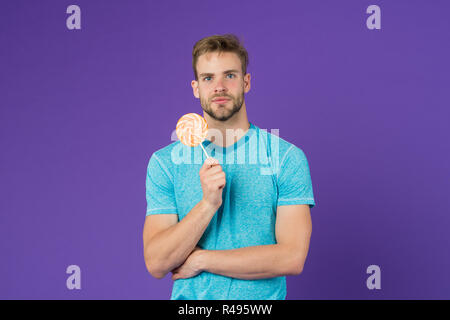 Lollipop Spaß. Mann essen großen bunten süßen Lutscher. Mann mit Borsten mag Lollipop. Cheat meal Konzept. Zucker schädlich für die Gesundheit. Kerl halten Lollipop ca Stockfoto