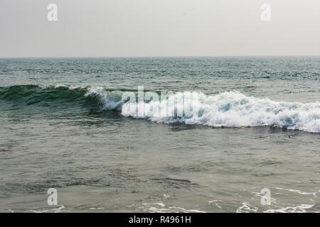 Yarada Strand mit indischen Ozeanwellen, die auf die Uferfelsen und -Steine krachen. Langzeitbelichtung mit seidig glattem Wasser und Felsen im Hintergrund. Stockfoto