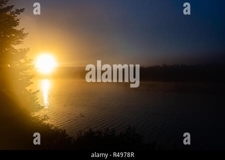 Misty Sonne über Big Trout Lake Stockfoto