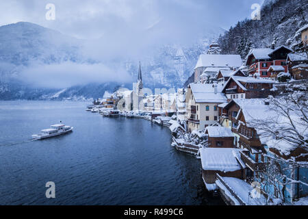 Klassische Postkarte Blick auf berühmte Hallstatt Stadt am See mit traditionellen Passagierschiff auf hallstattersee See auf einem Moody bewölkten Tag mit mystischen Nebel ich Stockfoto