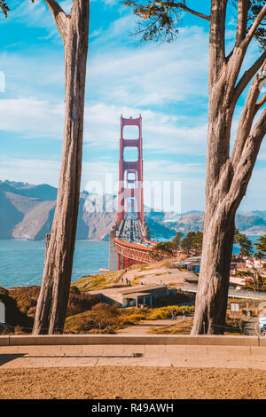 Berühmte Golden Gate Bridge von alten Zypressen bei Scenic Presidio Park gerahmt an einem schönen sonnigen Tag mit blauen Himmel und Wolken, San Francisco, USA Stockfoto