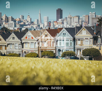 Klassische Postkarte Ansicht des berühmten gemalten Damen, eine Reihe von bunten viktorianische Häuser am Alamo Square gelegen, mit Blick auf die Skyline von San Francisco im b Stockfoto