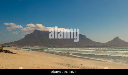 Kapstadt, Südafrika - ein nicht identifizierter beachgoer auf Milnerton Beach an einem windigen Tag mit dem Tafelberg im Hintergrund Stockfoto