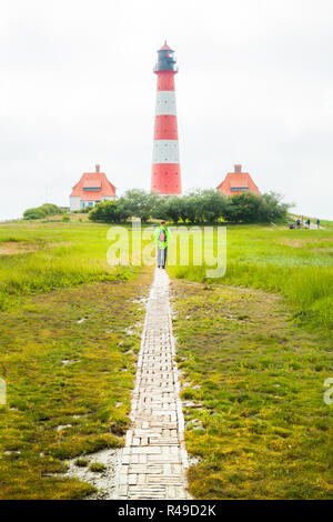 Menschen auf dem Weg zu bekannten Westerheversand an einem sonnigen Tag mit blauen Himmel und Wolken im Sommer, Nordsee, Schleswig-Holstein, Deutschland Stockfoto