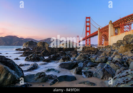 Berühmte Golden Gate Bridge View aus der versteckten und einsamen felsigen Marshall's Strand bei Sonnenuntergang in San Francisco, Kalifornien Stockfoto