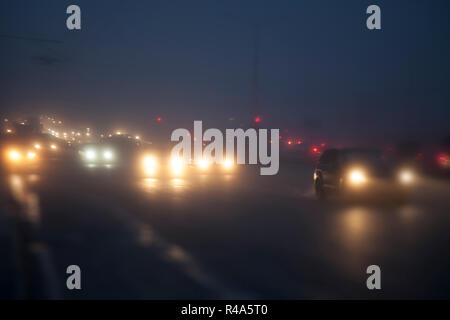 In der Nacht, im Licht der Laternen, Autos fahren im Nebel Stockfoto