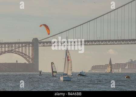 Ein Kitesurfer, Windsurfer, Segelboot, Motorboot und Fracht alle durch die Bucht von San Francisco mit der Golden Gate Bridge. Stockfoto