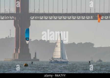 Zwei Kitesurfer und ein Segelboot unter der Golden Gate Bridge in der Bucht von San Francisco. Stockfoto