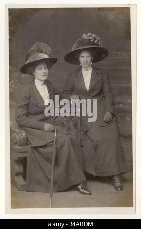 Original Edwardian Studio Porträt Postkarte von 2 edwardianischen Damen mit breitkrempigen Hüten, die mit Regenschirmen sitzen, Leeds, Großbritannien um 1909, 1910 Stockfoto