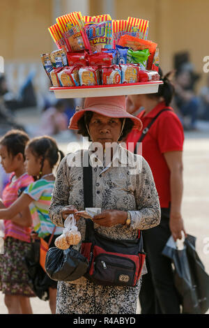 Frau Anbieter mit Fach von Snacks auf dem Kopf im Royal Palace Park. Preah Sisowath Quay, Stadtzentrum, Phnom Penh, Kambodscha Stockfoto