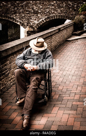 Ein Gentleman genießt ein Nickerchen am Nachmittag in seinem Rollstuhl. Stockfoto
