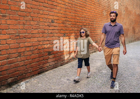 Jungen Sohn und Vater zusammen entlang Kopfsteinpflasterstraßen Stockfoto