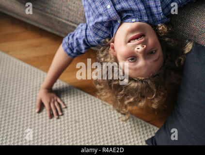 Kleiner Junge auf den Kopf von seinem Sofa im Wohnzimmer aufhängen Stockfoto