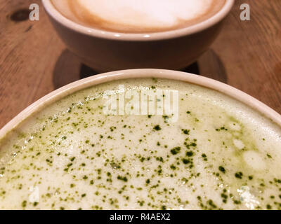 Nahaufnahme von eine Schale Matcha Latte und Cafe Latte auf einer hölzernen Tisch. Stockfoto
