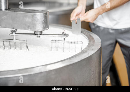 Man mischen Milch in der Edelstahl Tanks während der Fermentation bei der Käseherstellung. Nahaufnahme mit kein Gesicht Stockfoto