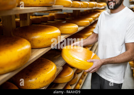 Arbeitnehmer, die Käse bei der Lagerung während der Käse Alterungsprozess. Nahaufnahme mit kein Gesicht Stockfoto