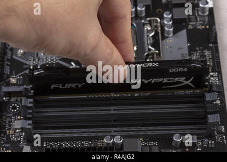 Maykop, Russland - November 9, 2018: Man installiert ein DDR4 DIMM 16 Gb Kingston HyperX Fury Speicher RAM-Modul in den Steckplatz auf dem Motherboard closeup Stockfoto