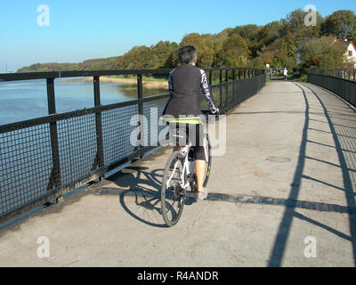 Um die UK-Verkehr kostenlose Radfahren - Eine einzige weibliche Radfahrer Überqueren der Causeway über den Fluss Condor Mündung bei Glasson Dock Stockfoto