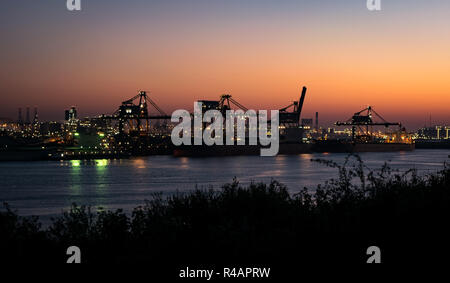 Industriekrane und Hafenbeleuchtung in der Dämmerung in Europoort, Hafen von Rotterdam, Niederlande Stockfoto