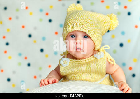 Porträt einer niedlichen neugeborenen Baby Mädchen in Gestrickt gelb Body und Hut auf Big Ball posing Stockfoto