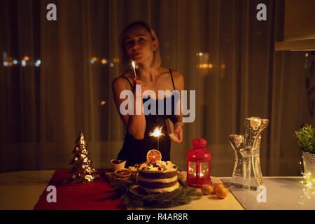 Junge Frau Beleuchtung eine Wunderkerze in den Kuchen in der Nacht zu Weihnachten Stockfoto