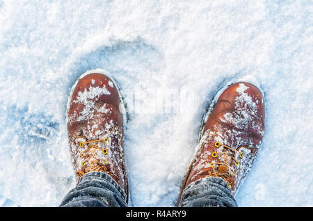 First Person Ansicht der Beine in Braun Stiefel im Schnee. Schnee auf Schuhe beim Gehen im Winter Stockfoto