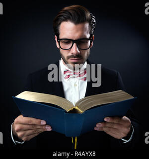 Geschäftsmann mit Brille lesen ein Buch fasziniert. Auf schwarz isoliert. Stockfoto