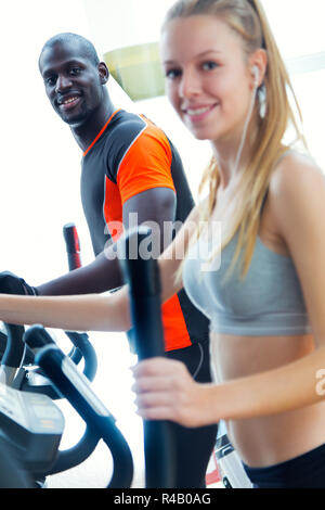 Junge Menschen mit elliptischen Maschine in der Turnhalle. Stockfoto