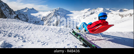 Junge glücklich attraktive Skifahrer auf der Oberseite der Berge genießen der Aussicht von Presena Gletscher, Tonale, Italien sitzen. Stockfoto