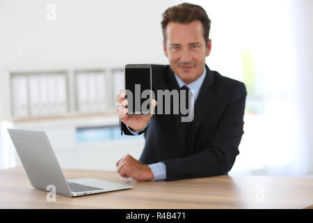 Geschäftsmann Holding und zeigt Smartphone in Richtung Kamera Stockfoto