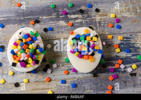 Minimalismus Konzept. Unerwartete Konzept. Flach, zwei Eier, gefüllt mit bunten kleinen tmosaic, über blauen Hintergrund. Stockfoto