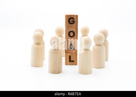 Holzfiguren als Business Team im Kreis um Wort Ziel, auf weißem Hintergrund, minimalistisches Konzept Stockfoto