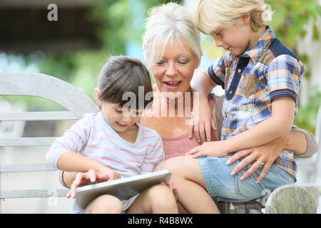 Großmutter mit Kindern spielen auf Tablet Stockfoto