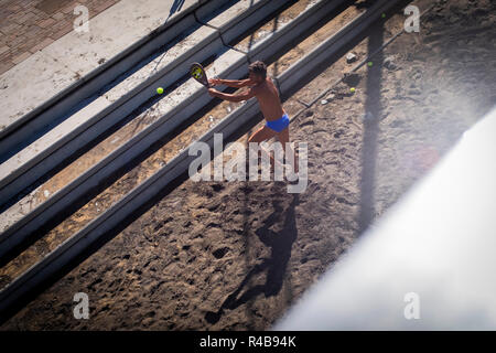 Ein Mann spielt Schläger am Strand Stockfoto