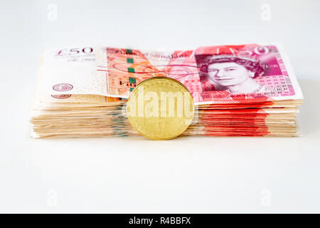 Bitcoin mit einem Stapel von 50 Pfund Sterling bank Notes Stockfoto