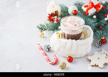 Heiße Schokolade oder Kakao mit Schlagsahne und Zuckerstange zum Dessert. Traditionelle weihnachtliche Getränke Konzept. Geschenke und Dekorationen, Copyspace. Stockfoto