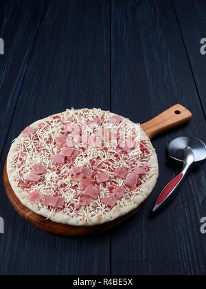Gefrorene Pizza mit Schinken auf einem rostigen Fach, auf einem dunklen Hintergrund Stockfoto