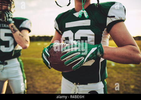 Nahaufnahme eines American Football quarterback stehend mit einem Mannschaftskameraden während einer Praxis Sitzung außerhalb auf einem Sportplatz am Nachmittag Stockfoto