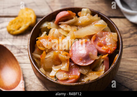 Gedünstetem Rosenkohl mit Würstchen in hölzernen Schüsseln auf den Tisch. Selektiver Fokus Stockfoto