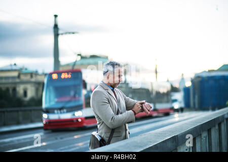 Reifen Geschäftsmann stand auf einer Brücke in Prag, die Zeit der Überprüfung. Stockfoto