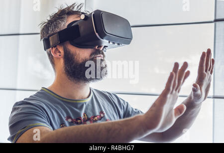 Porträt der jungen bärtigen Mann mit Virtual Reality im futuristischen Design Brille. Ausdruck der Verwunderung im Gesicht Stockfoto