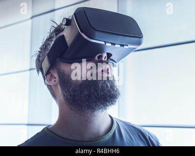 Porträt der jungen bärtigen Mann mit Virtual Reality im futuristischen Design Brille. Ausdruck der Verwunderung im Gesicht Stockfoto
