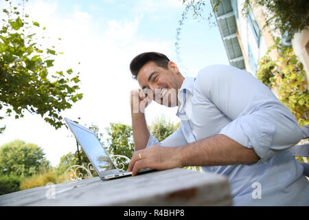 Reifer Mann am Wochenende von zu Hause aus arbeiten mit Laptop Stockfoto