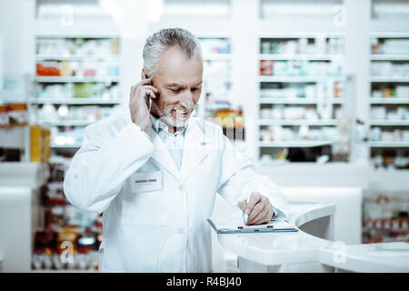 Daten Überprüfung. Ältere Arbeitnehmer im Gespräch per Telefon, während sie Hinweise erfreut Stockfoto