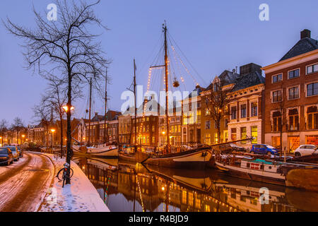 Historische Gebäude auf verschneiten Hoge der Aa Kai mit Schiff in Groningen Innenstadt bei Sonnenuntergang rund um Weihnachten, Niederlande Stockfoto