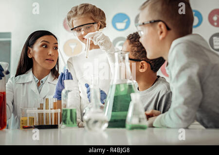 So aufregend. Fröhliches Mädchen tragen Schutzbrille beim chemischen Experimentieren Stockfoto