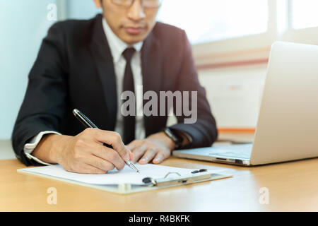 Unternehmer unterzeichnen Vertrag Papier mit Stift und Laptop im Büro Schreibtisch. Stockfoto